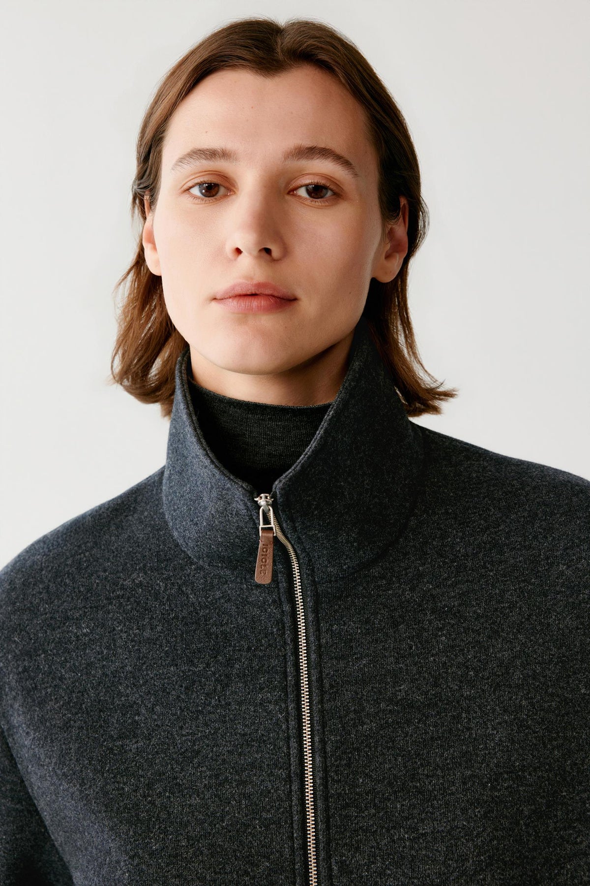 Close-up highlighting the stand collar, zip fastening and grey melange jersey texture.