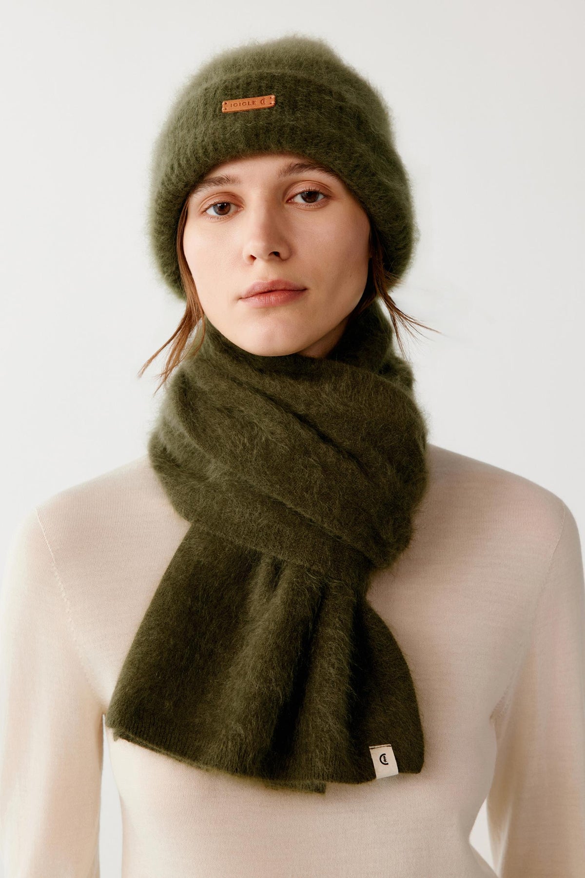 Front view of a woman wearing the dark green brushed cashmere scarf wrapped around the neck, showing the long ends and brushed texture.