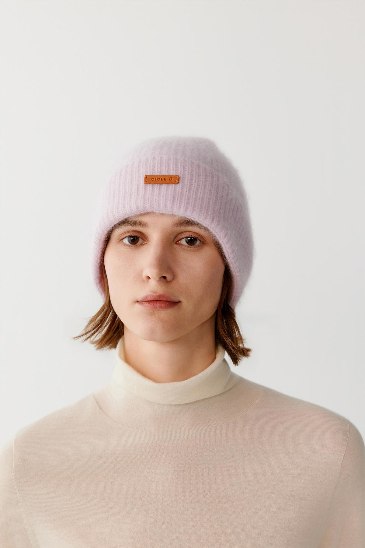 Front close-up of a woman wearing the light pink brushed cashmere beanie, highlighting the turned-up cuff and brushed texture.
