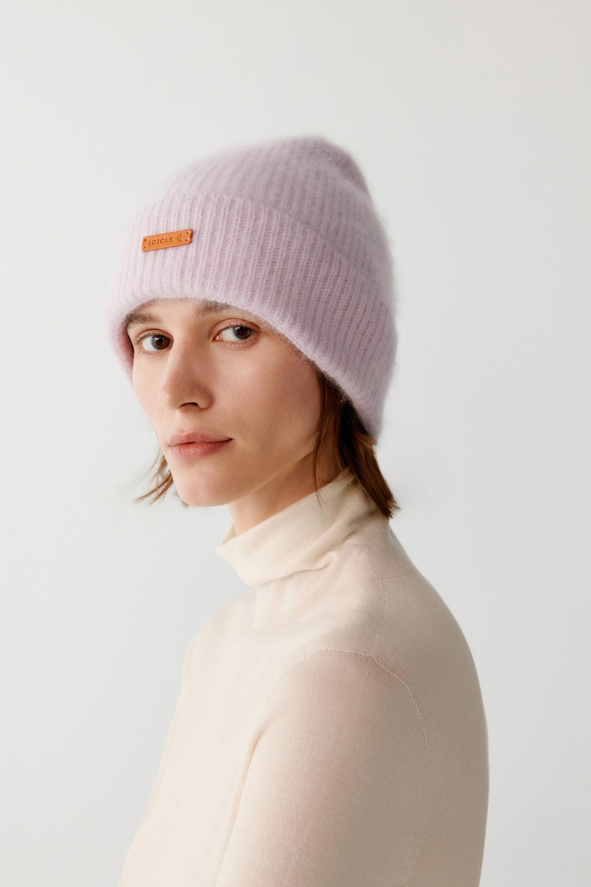 Three-quarter view of a woman wearing the light pink brushed cashmere beanie, showing the rounded crown and turned-up cuff.