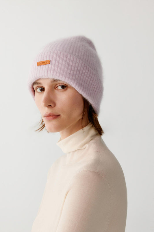 Three-quarter view of a woman wearing the light pink brushed cashmere beanie, showing the rounded crown and turned-up cuff.