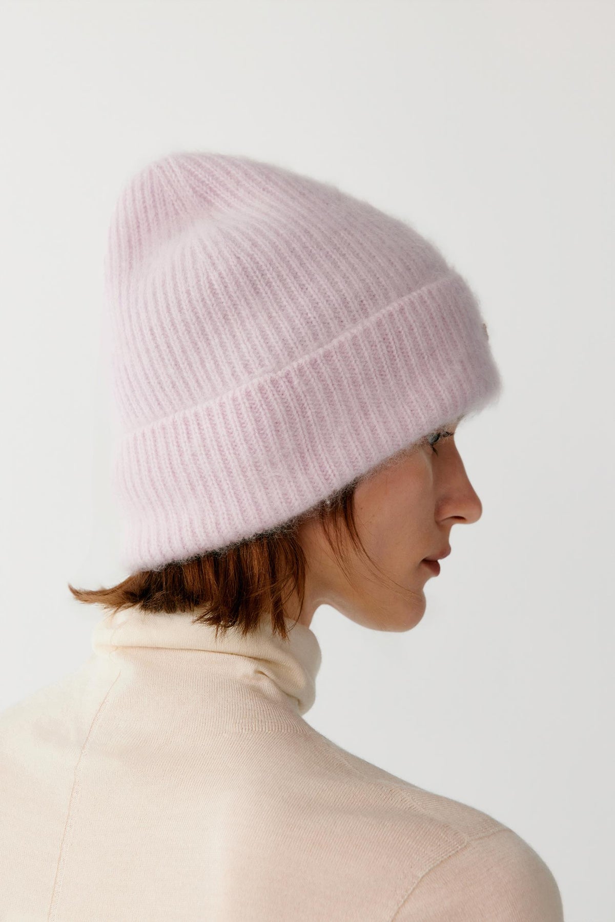 Back view of a woman wearing the light pink brushed cashmere beanie, highlighting the rounded crown and brushed texture.