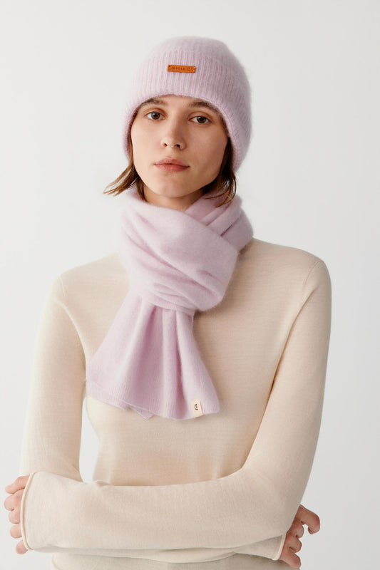 Front view of a woman wearing a light pink brushed cashmere beanie, showing the ribbed turned-up cuff and rounded crown.