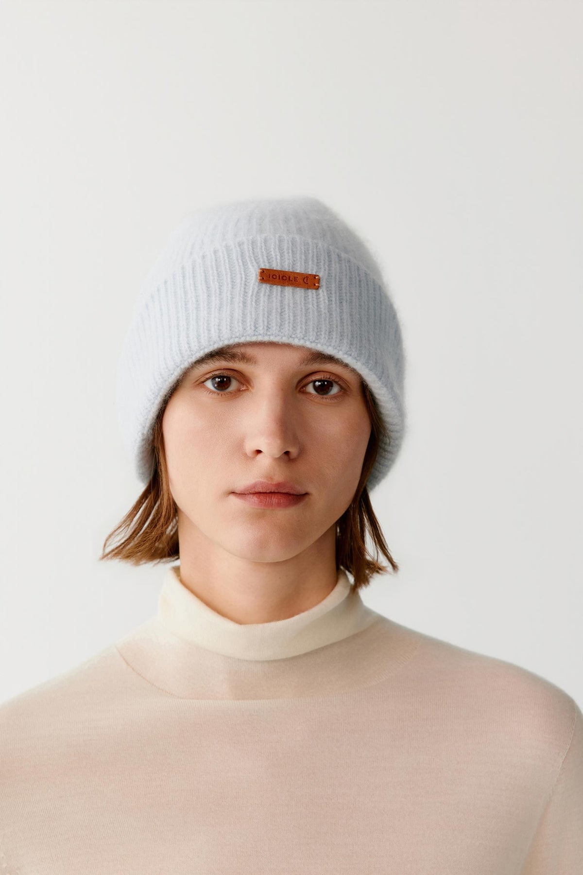 Front view of a woman wearing a light blue brushed cashmere beanie, showing the ribbed turned-up cuff and rounded crown.