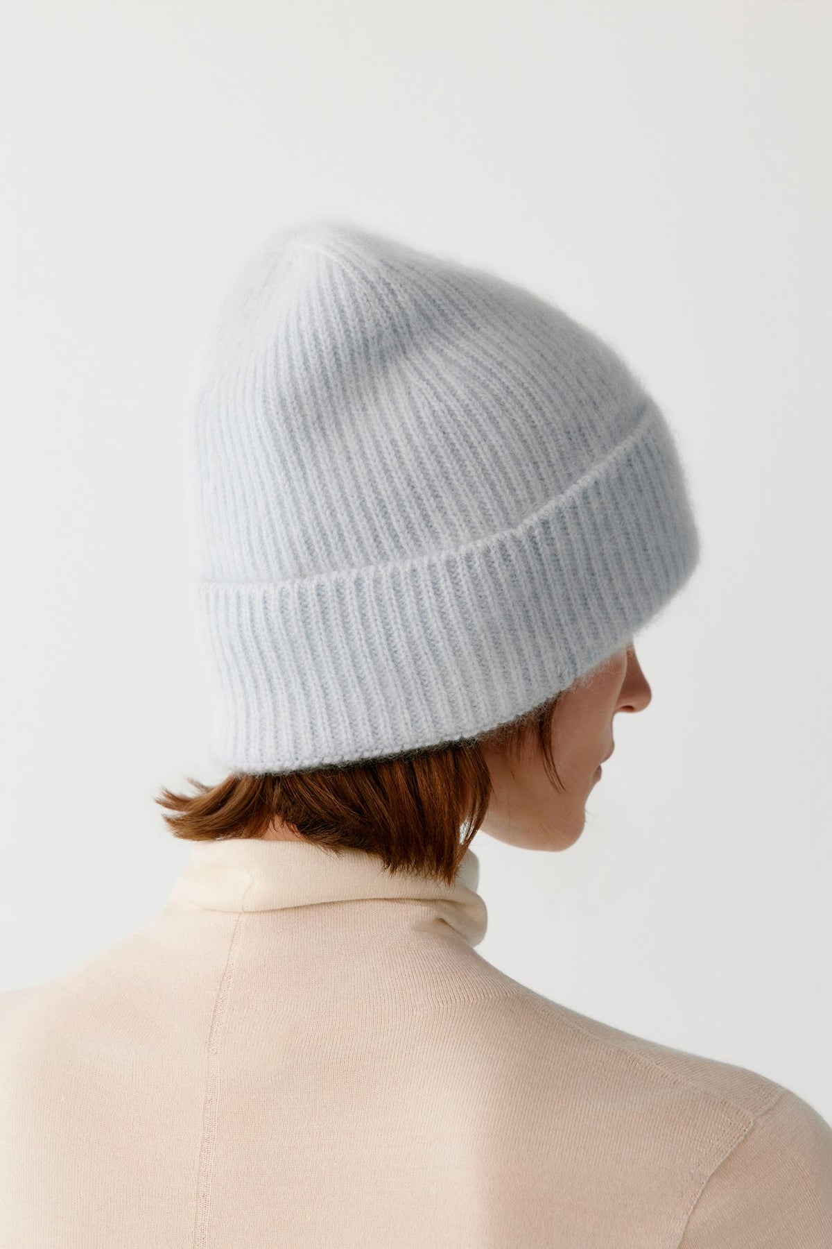 Back view of a woman wearing the light blue brushed cashmere beanie, highlighting the rounded crown and brushed texture.