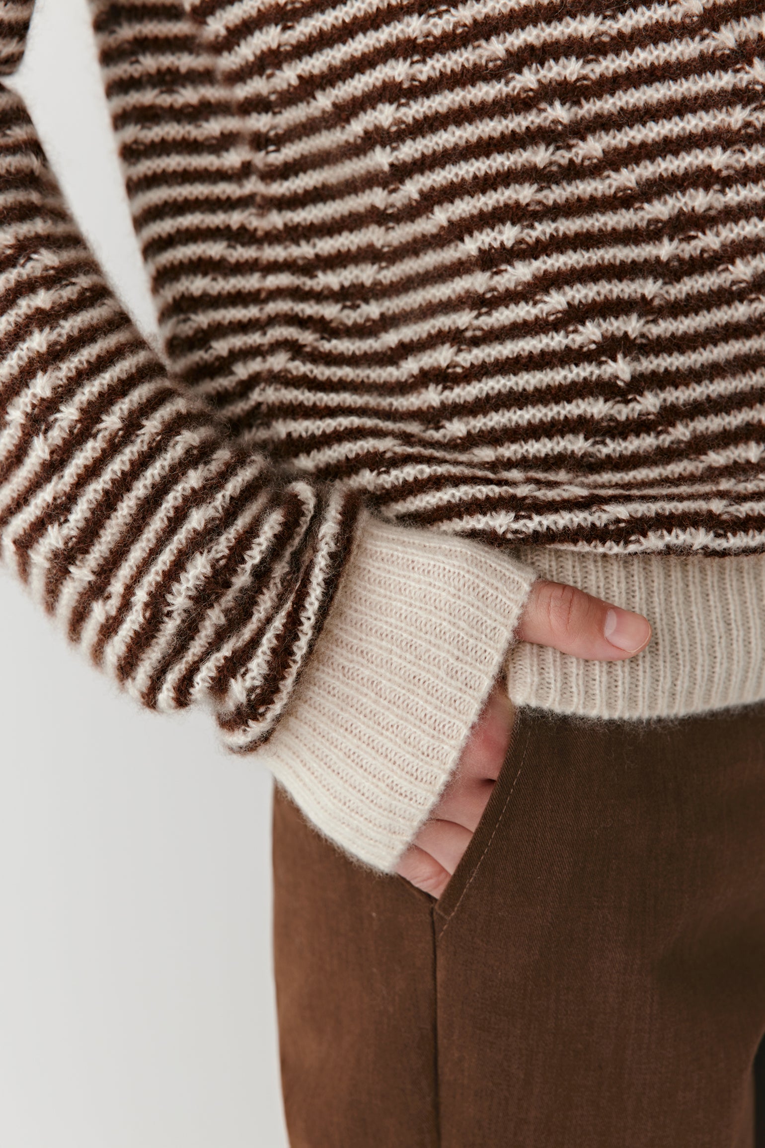Close-up of the striped cashmere-silk pullover’s neckline and upper chest, showing the fine knit texture and natural color contrast.