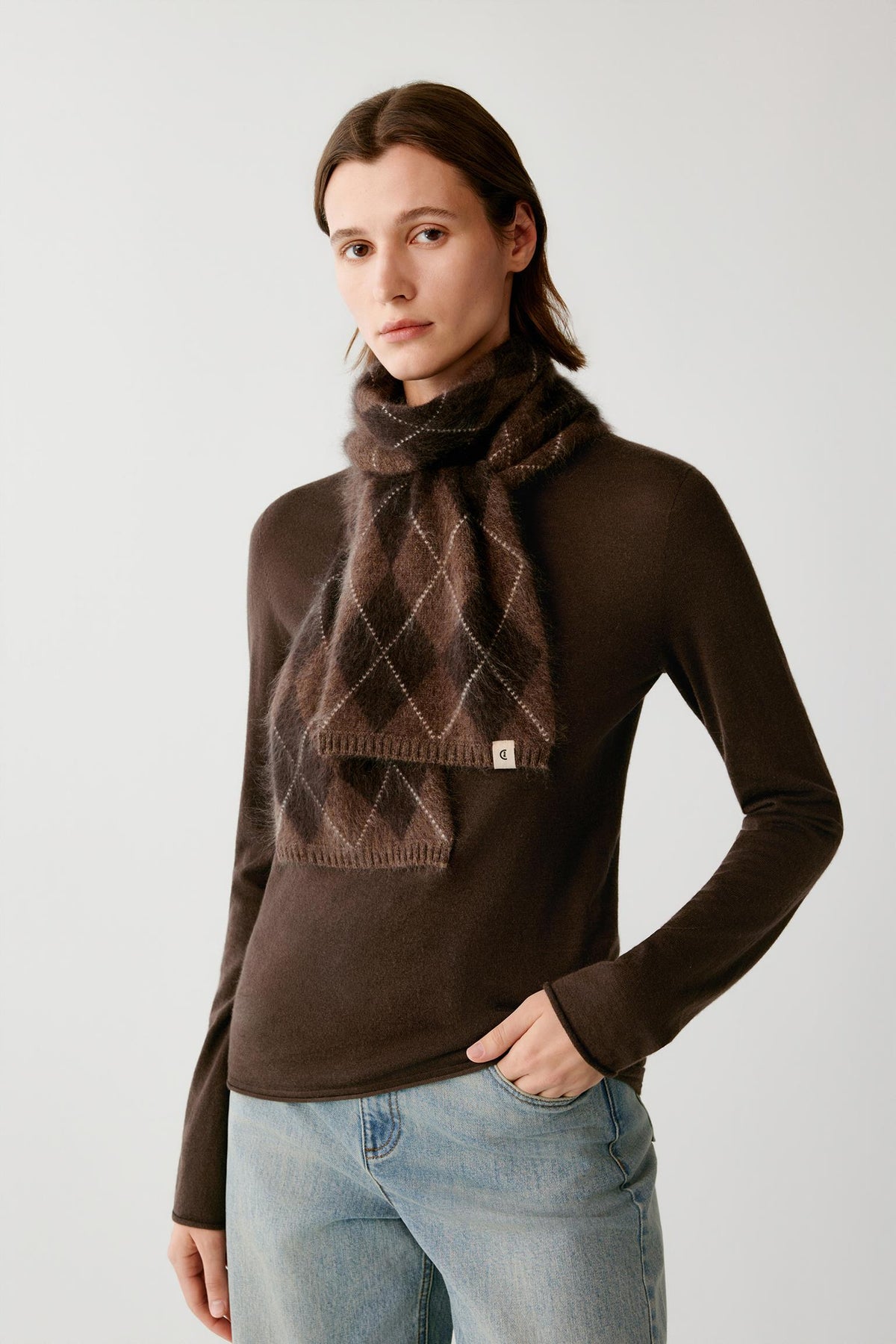 Front view of a woman wearing a dark brown brushed cashmere scarf with a contrasting argyle pattern.