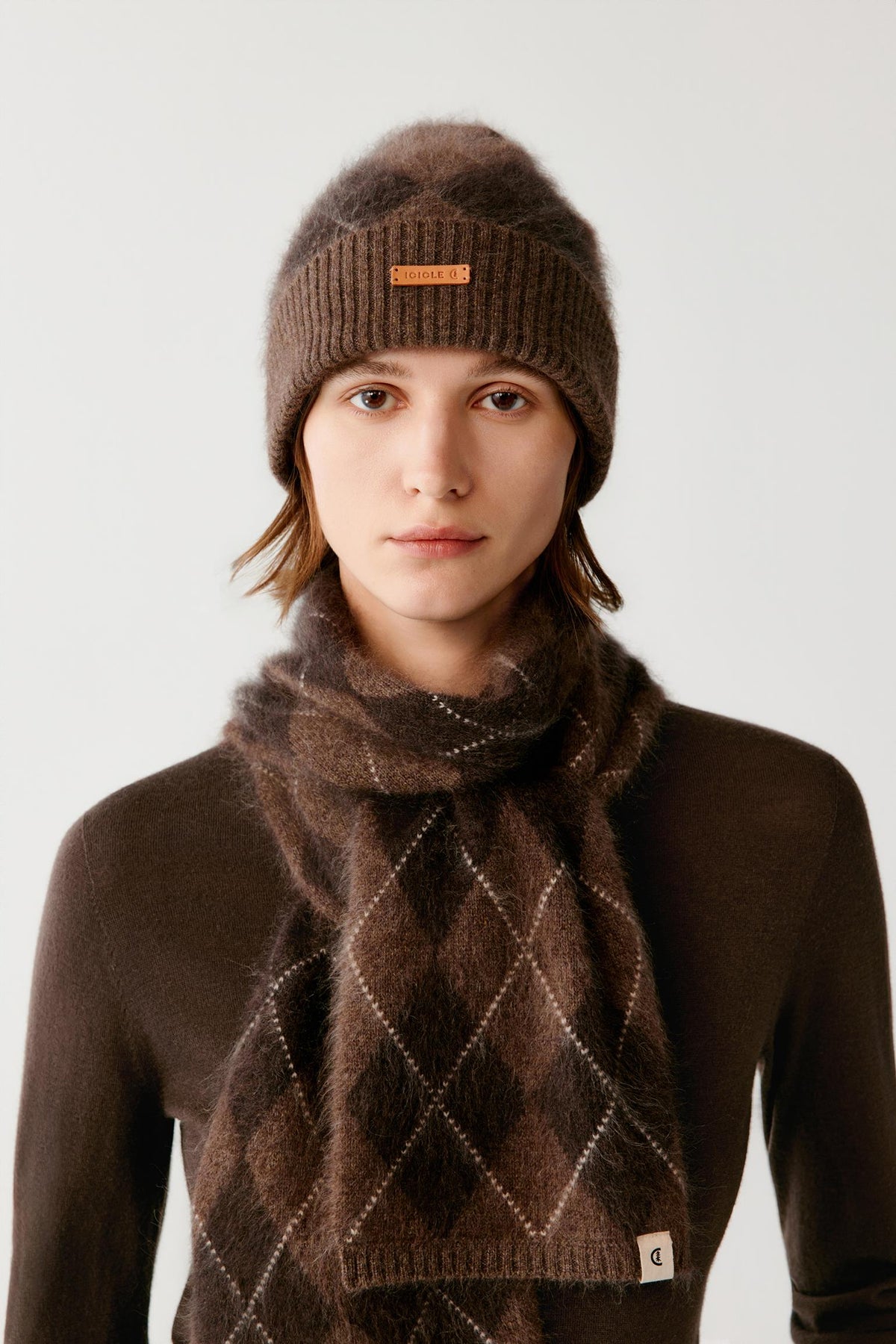 Front view of a woman wearing a dark brown brushed cashmere beanie, showing the ribbed turned-up cuff and rounded crown.