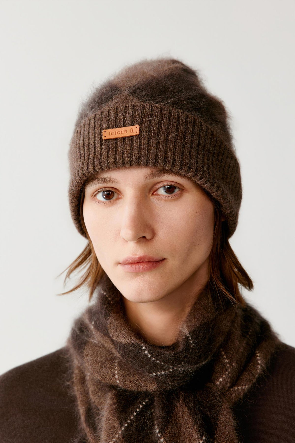 Front close-up of a woman wearing the dark brown brushed cashmere beanie, highlighting the turned-up cuff and brushed texture.