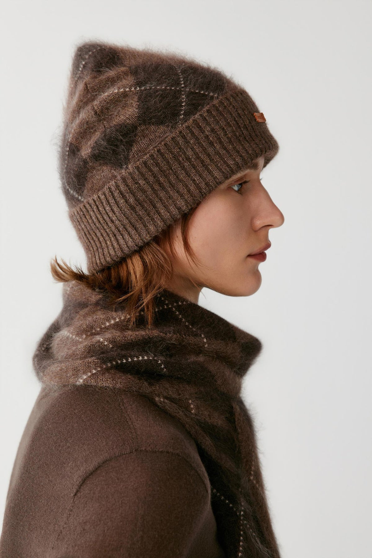 Side view of a woman wearing the dark brown brushed cashmere beanie, showing the rounded crown and ribbed turned-up cuff.