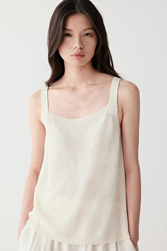 Front close-up view of a woman wearing a light cream linen-silk tank top with a fine knit structure, thin straps and soft square neckline, highlighting smooth texture and lightweight construction