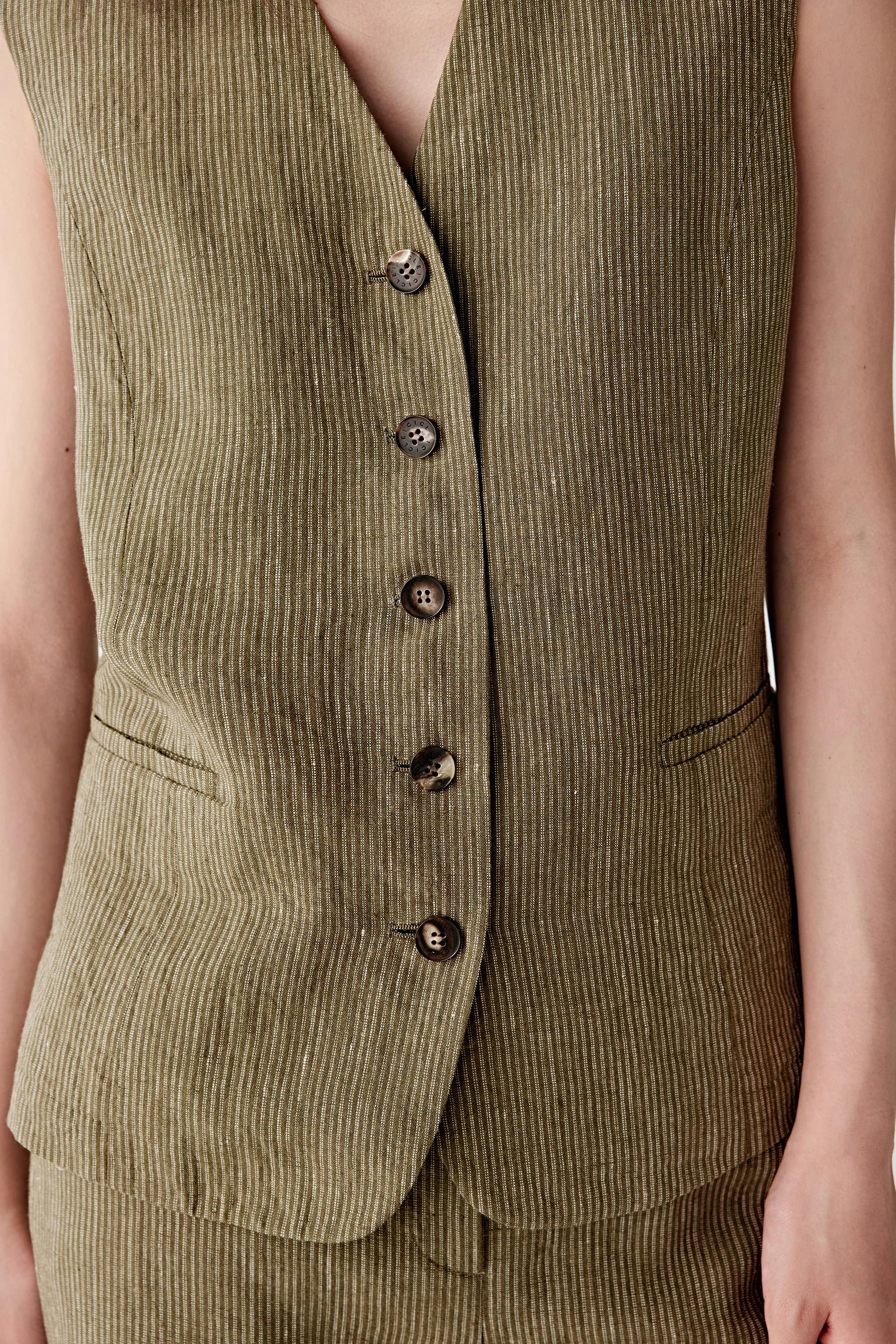 Close-up of the front panel focusing on the V neckline, tonal button fastening and the vertical striped pattern, showing stitching details and the slightly irregular texture of yarn-dyed linen