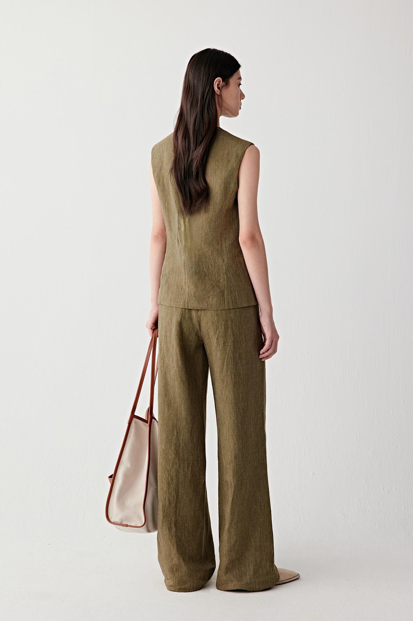 Full-length side view highlighting the slim profile, sleeveless cut and the way the linen fabric follows the body with a light, breathable structure while maintaining shape