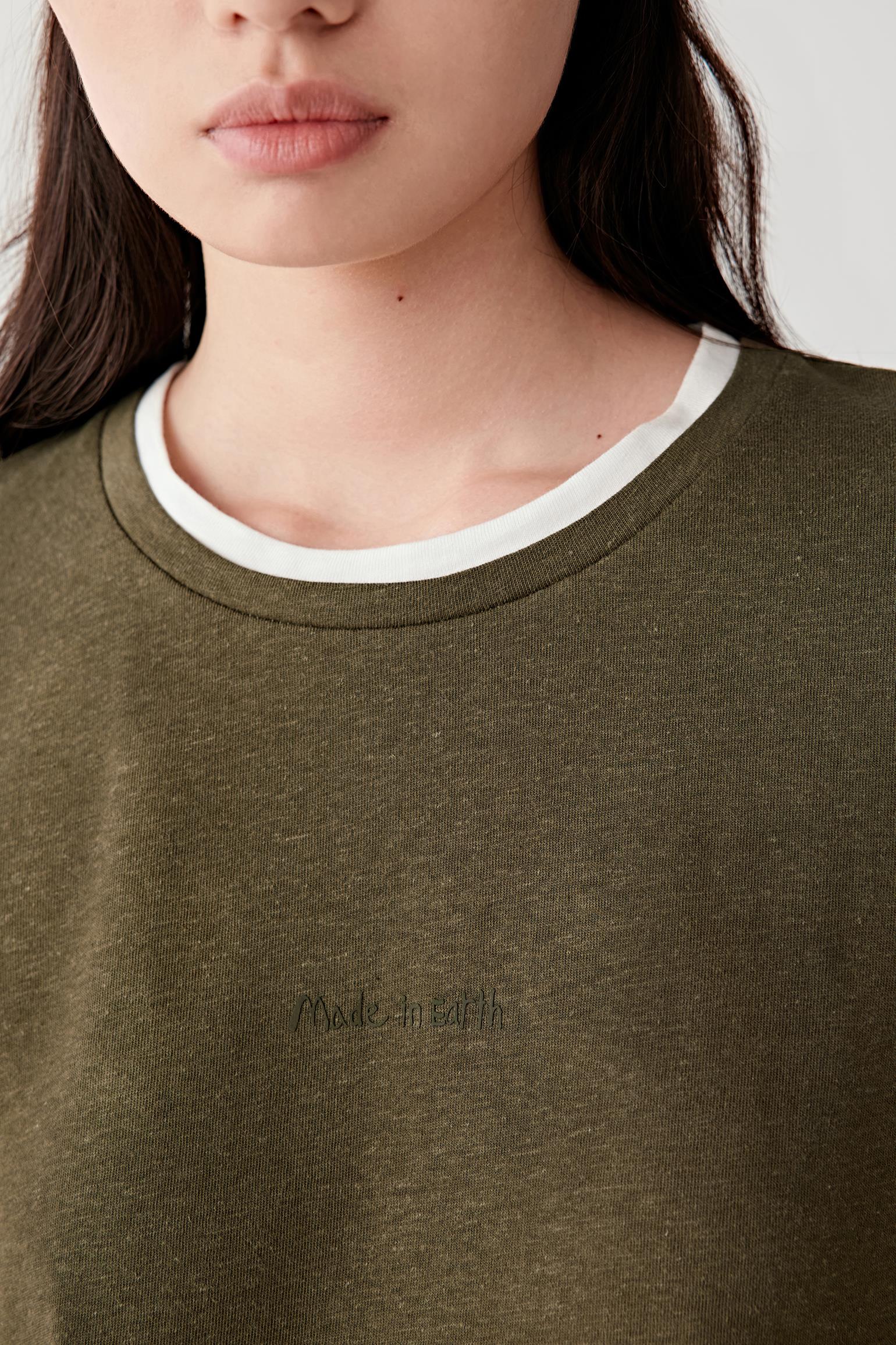 Close-up front view of neckline showing contrast trim, fine knit texture and slightly irregular natural fibre surface