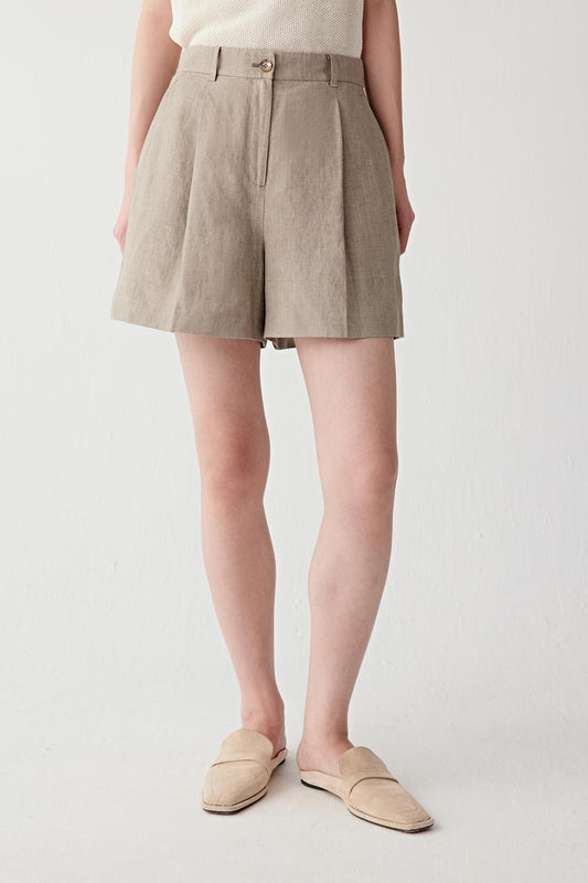 Front or three-quarter view emphasizing the high waist, pleated construction and relaxed silhouette, showing the fluid drape of the linen fabric