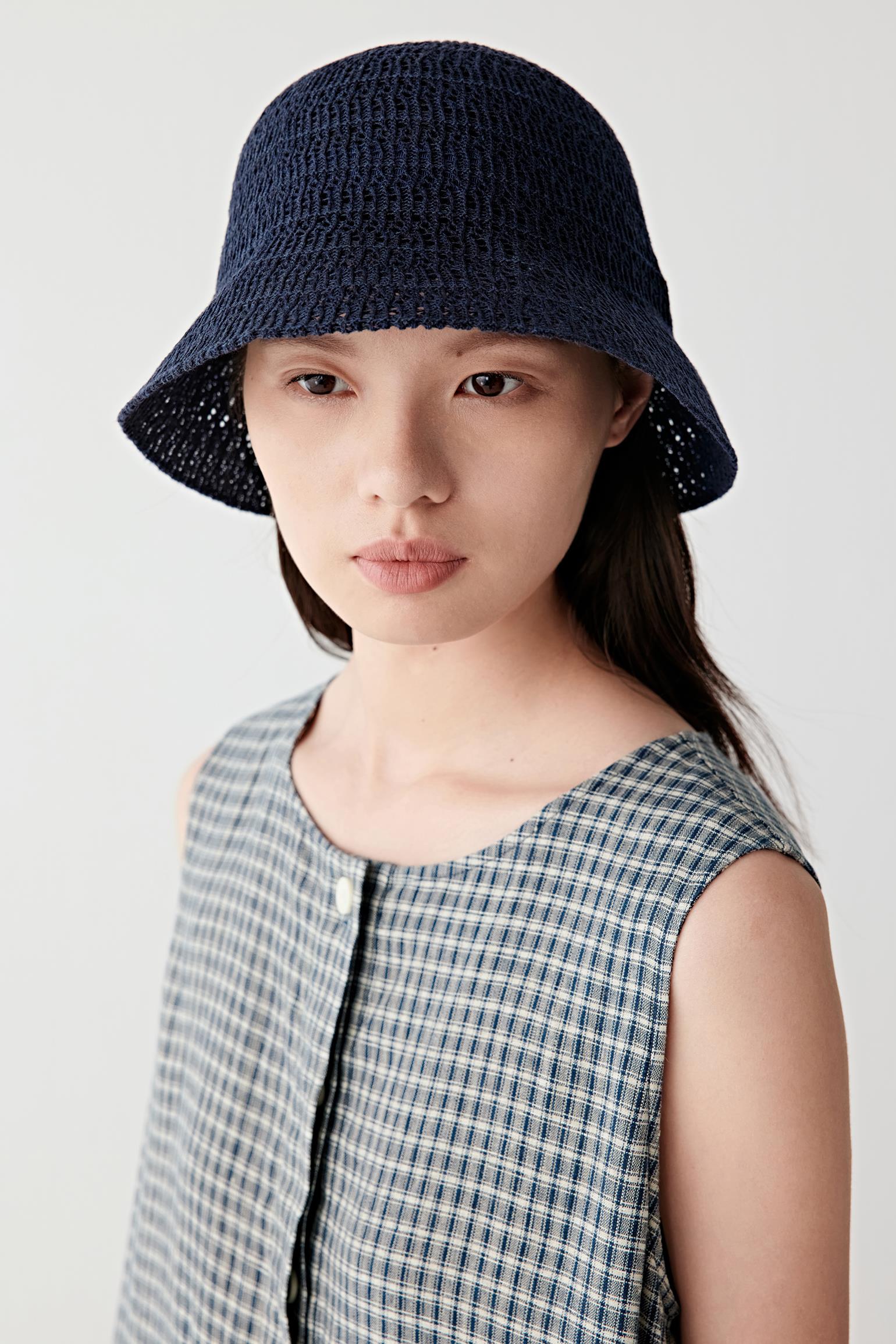 Three-quarter front view capturing the hat at an angle, showing how the crown sits close to the head, the even distribution of the knit pattern and the soft structure of the linen yarn