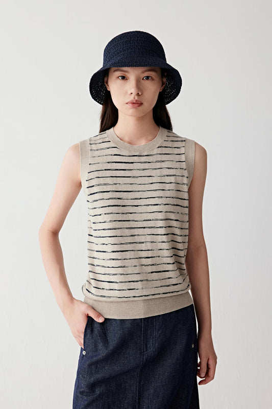 Front three-quarter view of a woman wearing a sleeveless striped linen-silk vest in beige and black tones, showing fitted yet relaxed silhouette, round neckline and lightweight knit