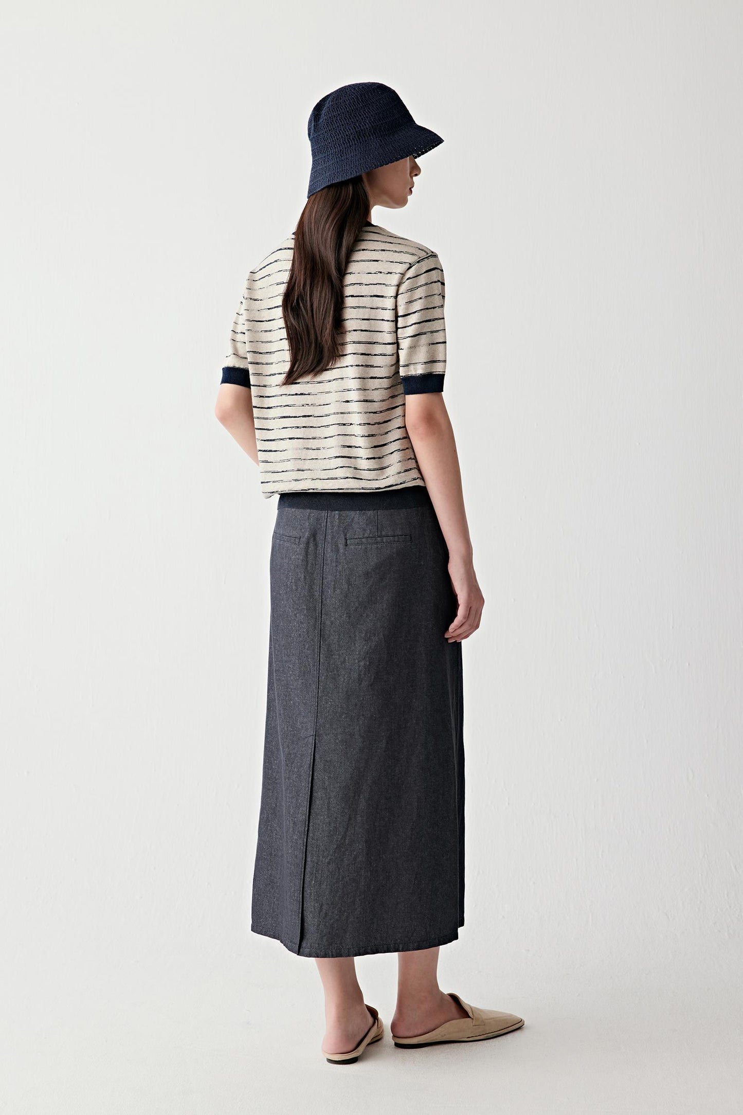 Three-quarter side view showing how the pullover falls loosely over the body and interacts with the skirt
