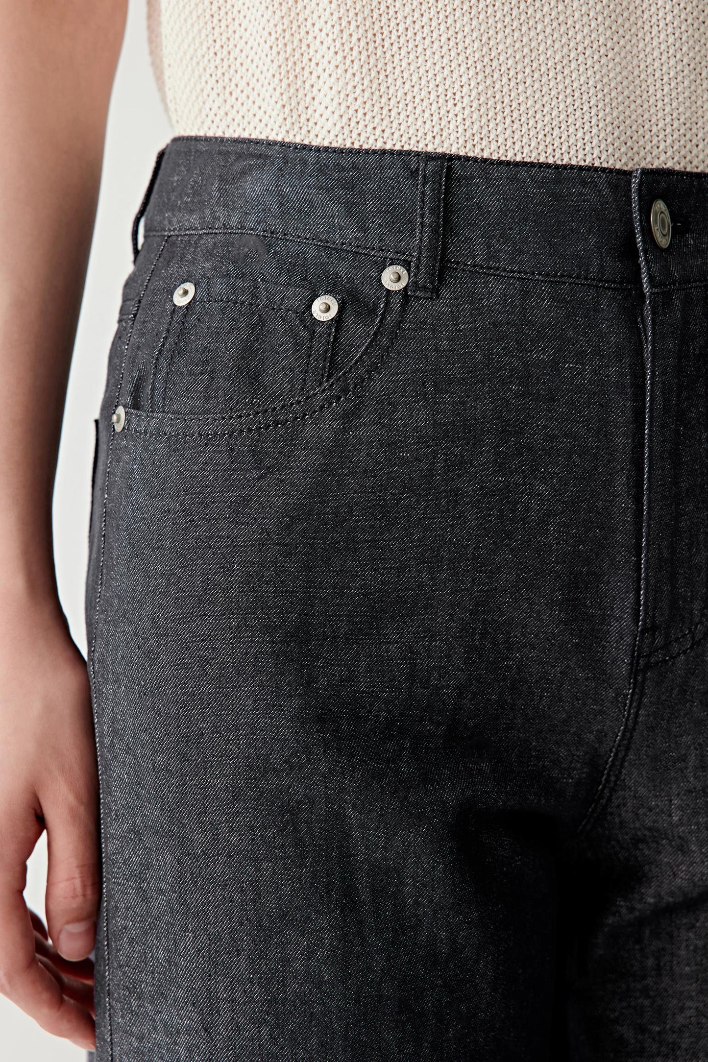 Close-up of the waistband and upper hip area, focusing on the structured waistband, metal button fastening and classic five-pocket construction, with visible stitching and subtle texture