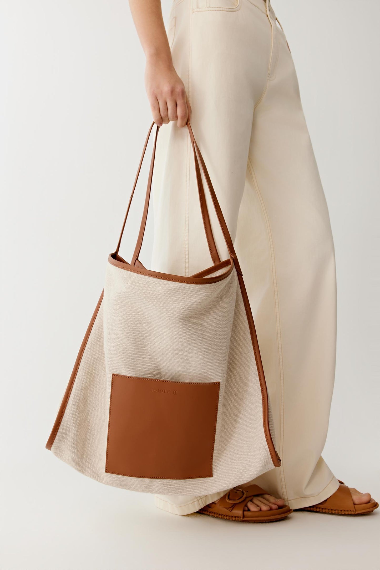 Side view highlighting the wide shoulder straps and the softly structured silhouette designed for comfortable everyday use.