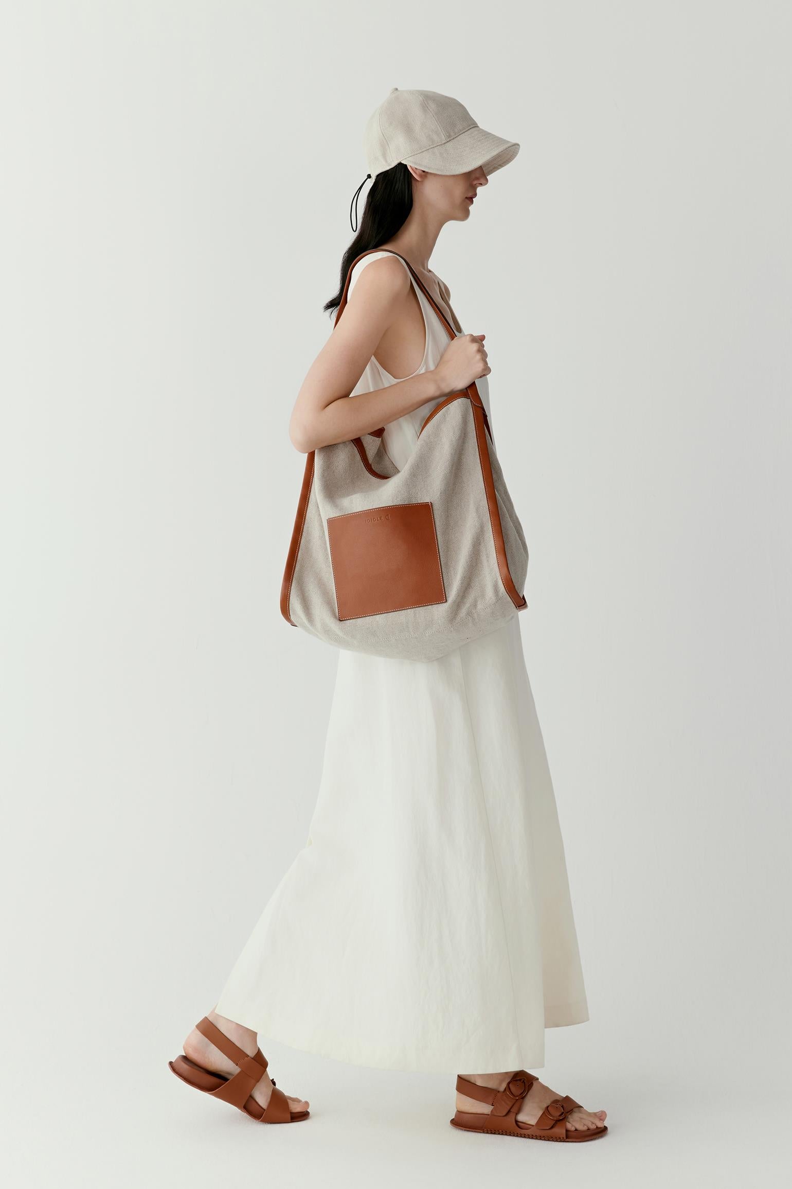 Full-length view showing the tote worn with a light summer outfit. The soft structure of the bag allows it to fall naturally along the body.