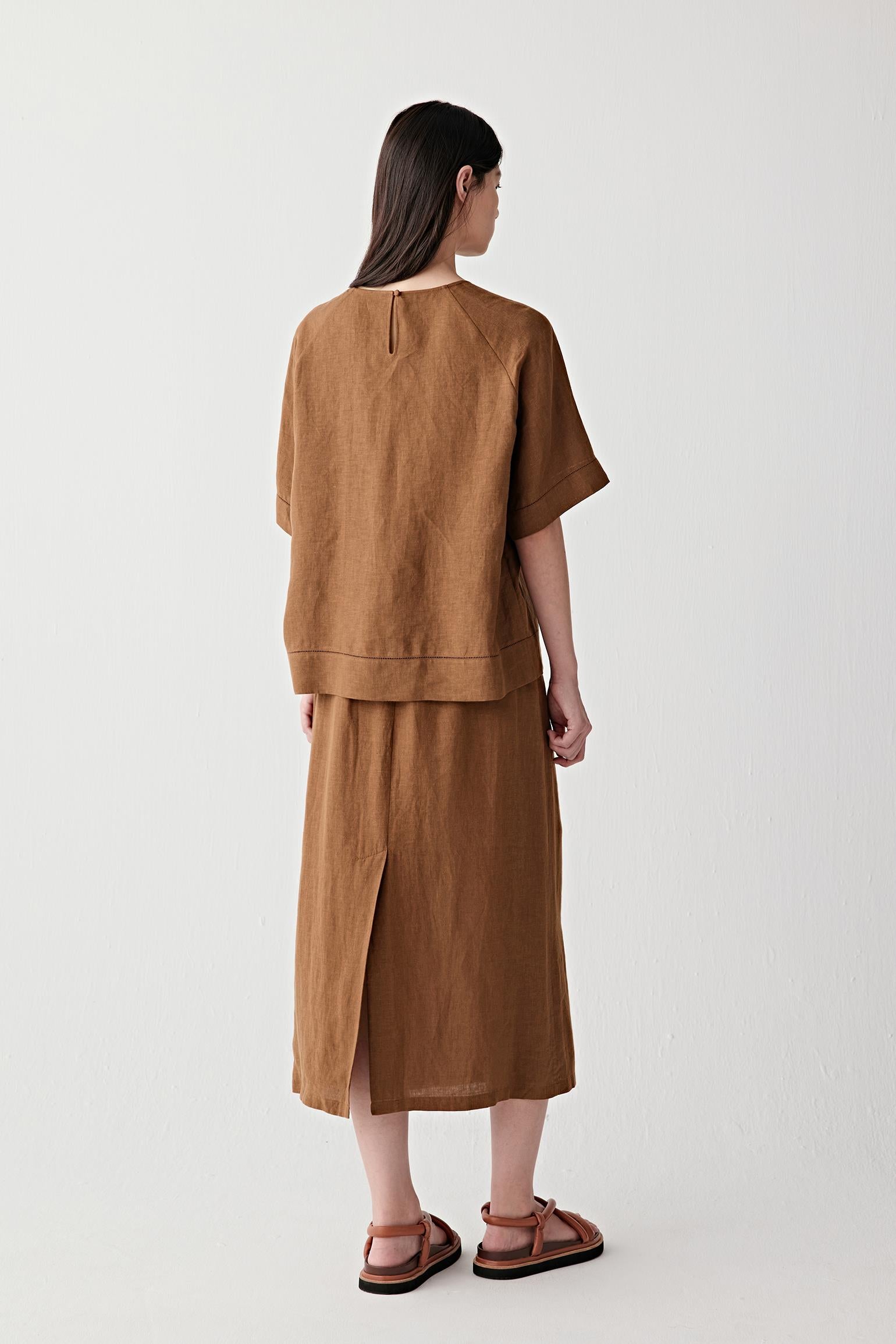 Full-length back view showing the top paired with a matching skirt, emphasizing the straight cut, lightweight structure and ease of movement created by the linen fabric