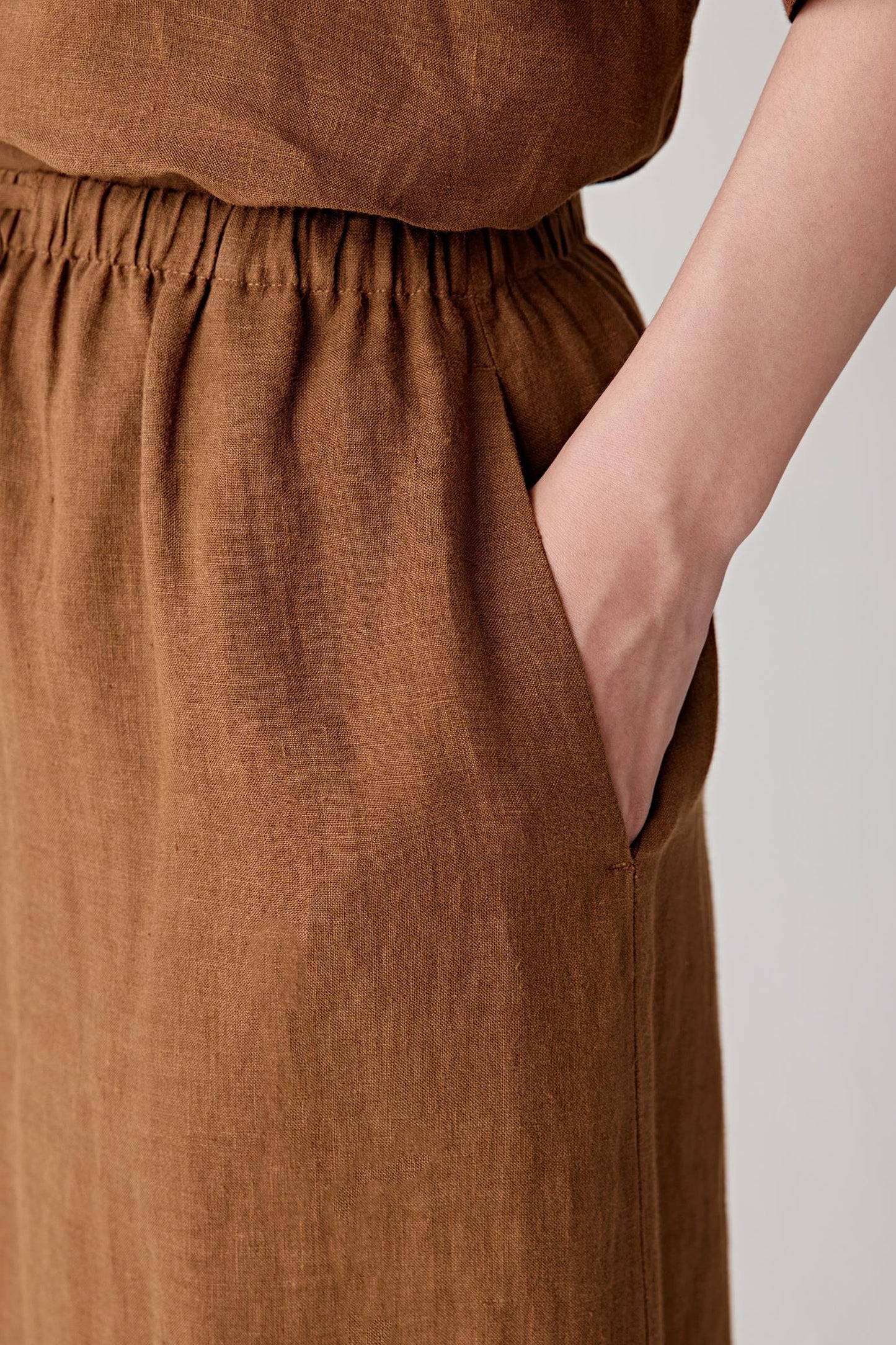 Close-up of side pocket and upper skirt showing the natural irregularities of the linen weave, lightly textured matte surface and softly structured drape of the fabric