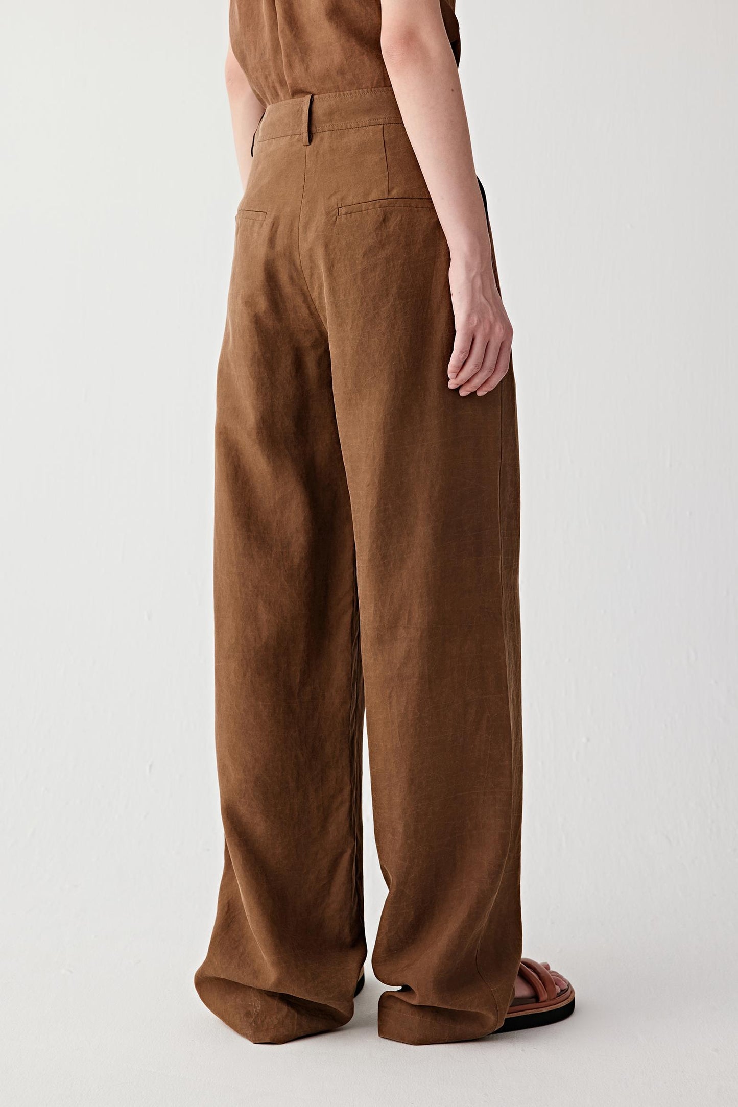 Full-length side or back view highlighting the clean line of the trousers, wide-leg cut and fluid drape through the silhouette