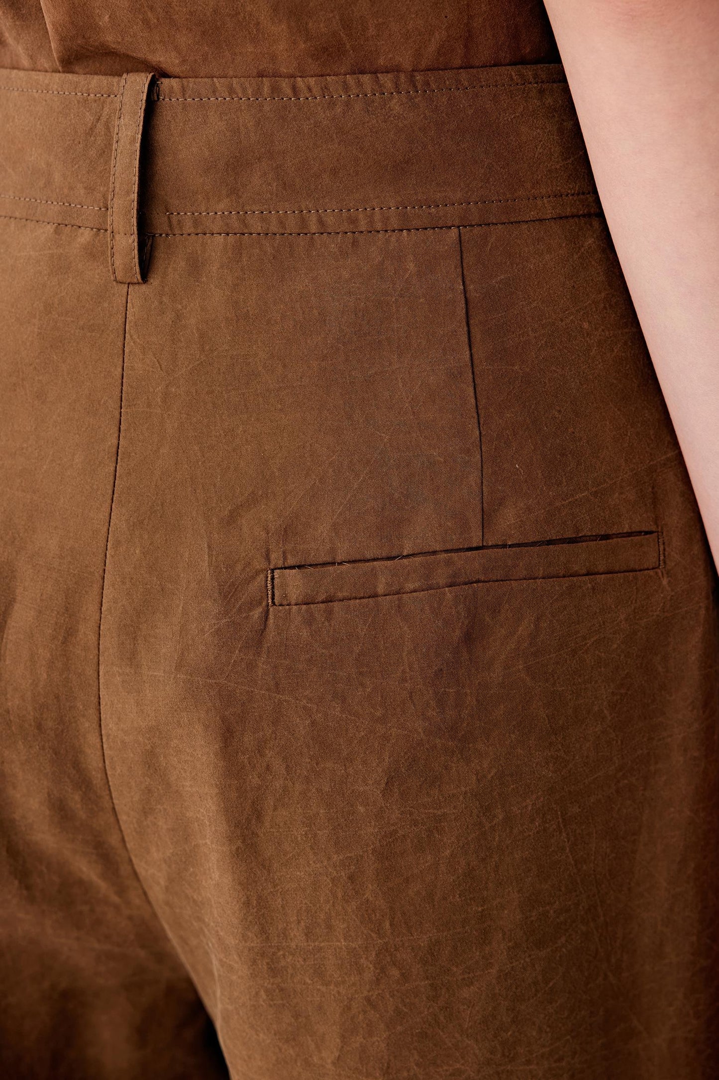 Close-up of side or back welt pocket showing visible stitching, tonal variation and the matte textured surface of the fabric