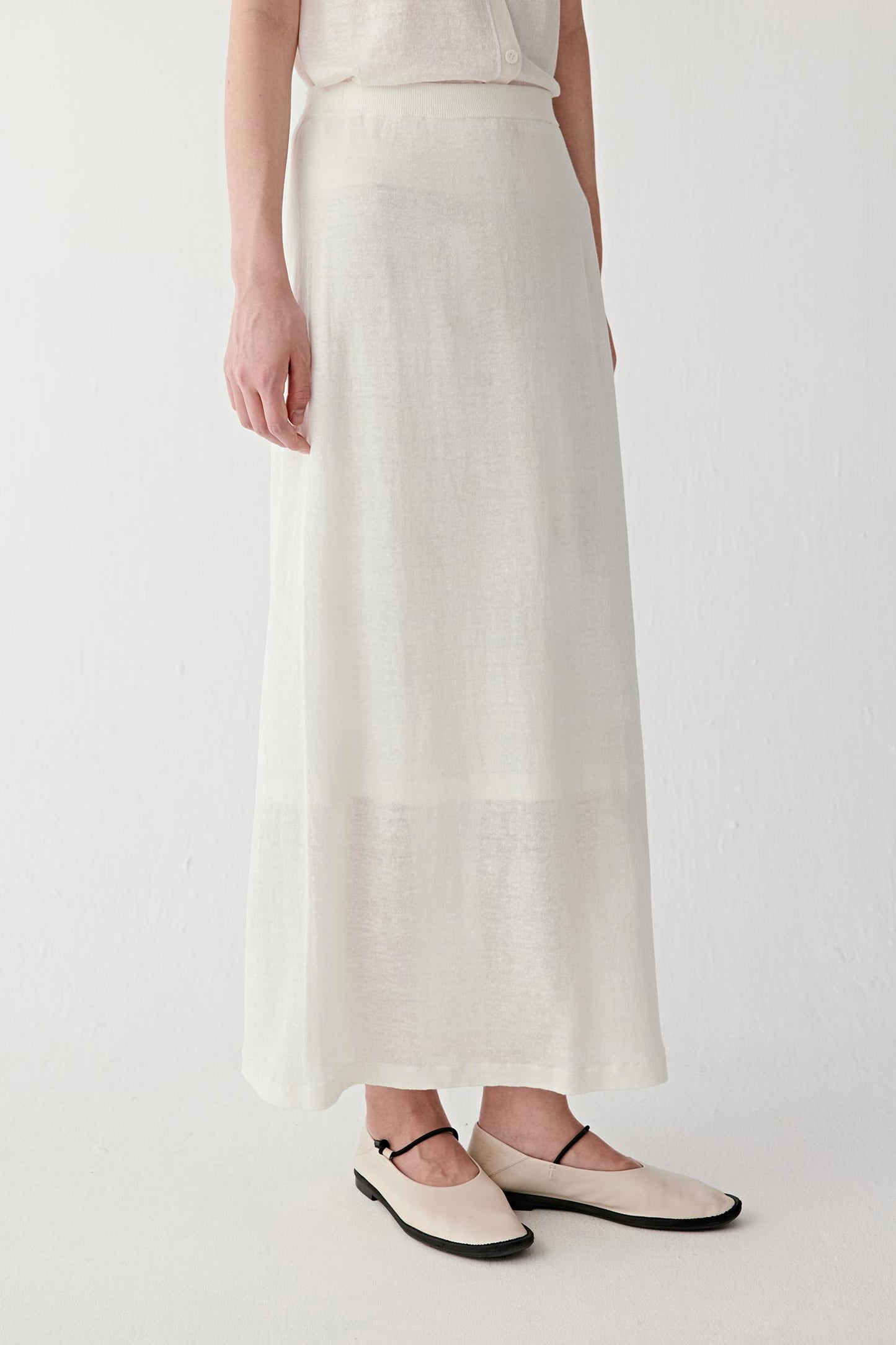 Close-up of waistband detailing the ribbed waistband construction, clean stitching and lightly textured off-white fabric surface with natural irregularity