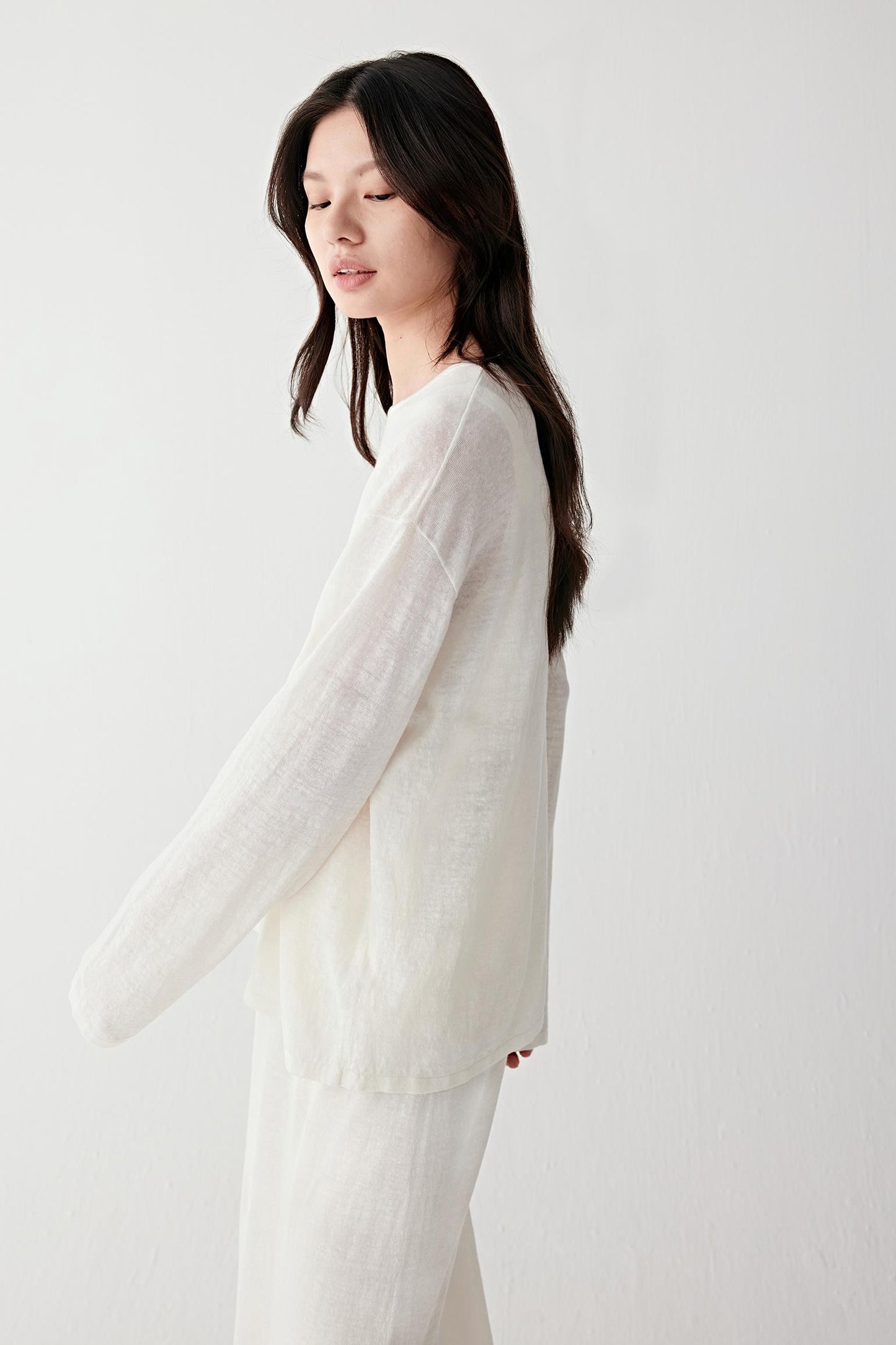 Close-up portrait focusing on the round neckline and upper knit structure, detailing the lightly sheer texture and soft matte finish