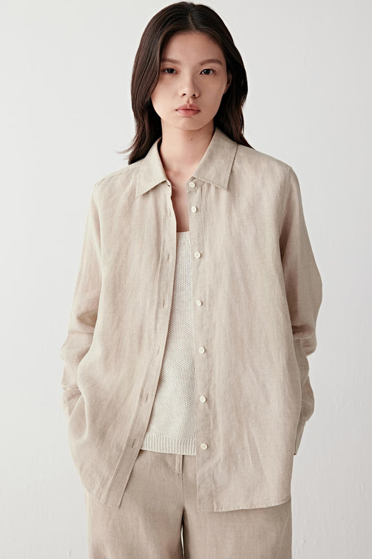Front view of a woman wearing a light brown melange linen shirt with a relaxed silhouette, highlighting the lightweight woven structure, fluid drape and softly textured matte surface