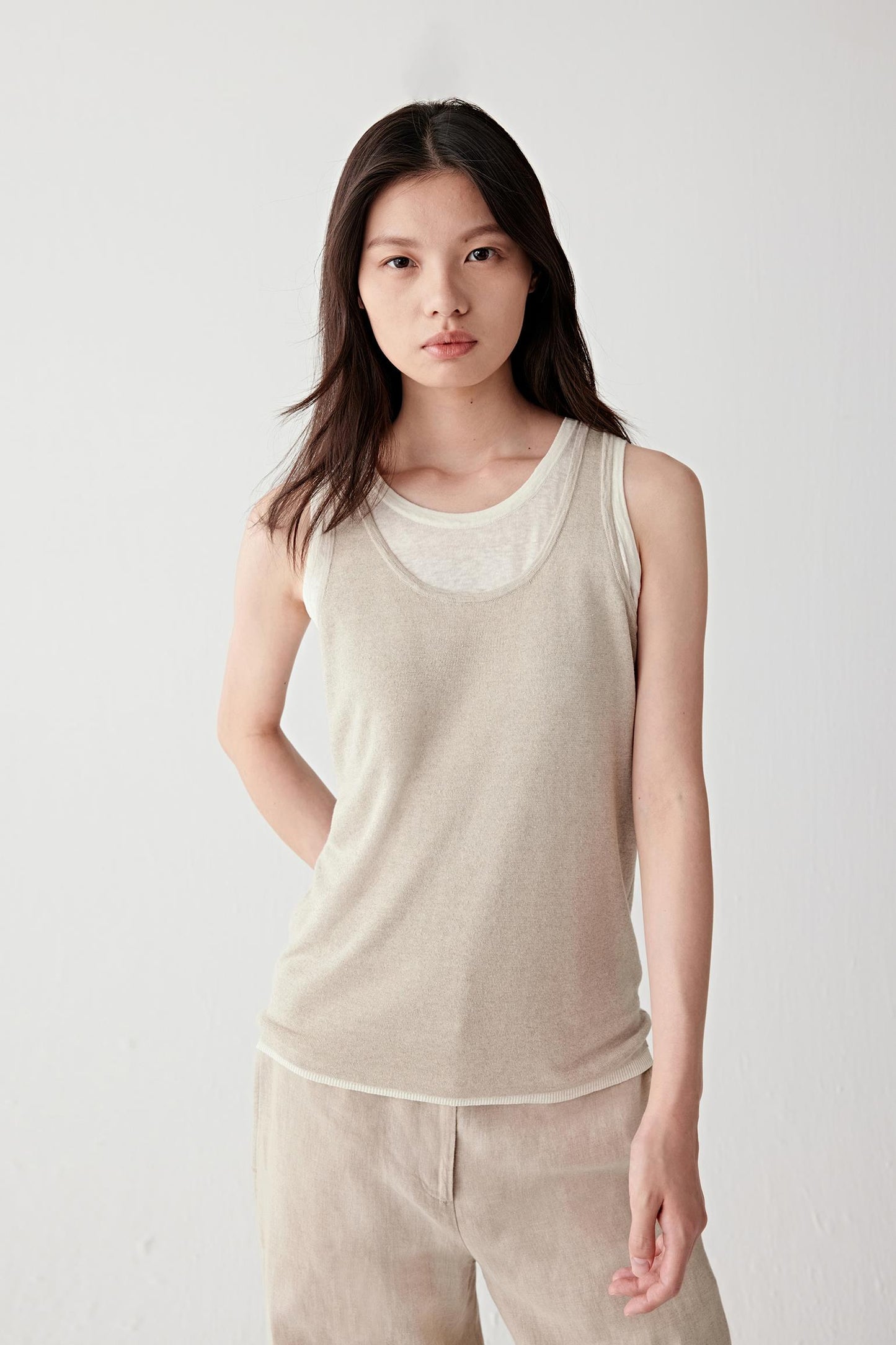 Full-length front view of a woman wearing a beige knitting top in linen and silk, highlighting the lightweight knit structure, subtle transparency and fluid drape