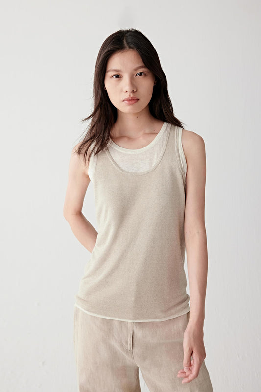 Full-length front view of a woman wearing a beige knitting top in linen and silk, highlighting the lightweight knit structure, subtle transparency and fluid drape