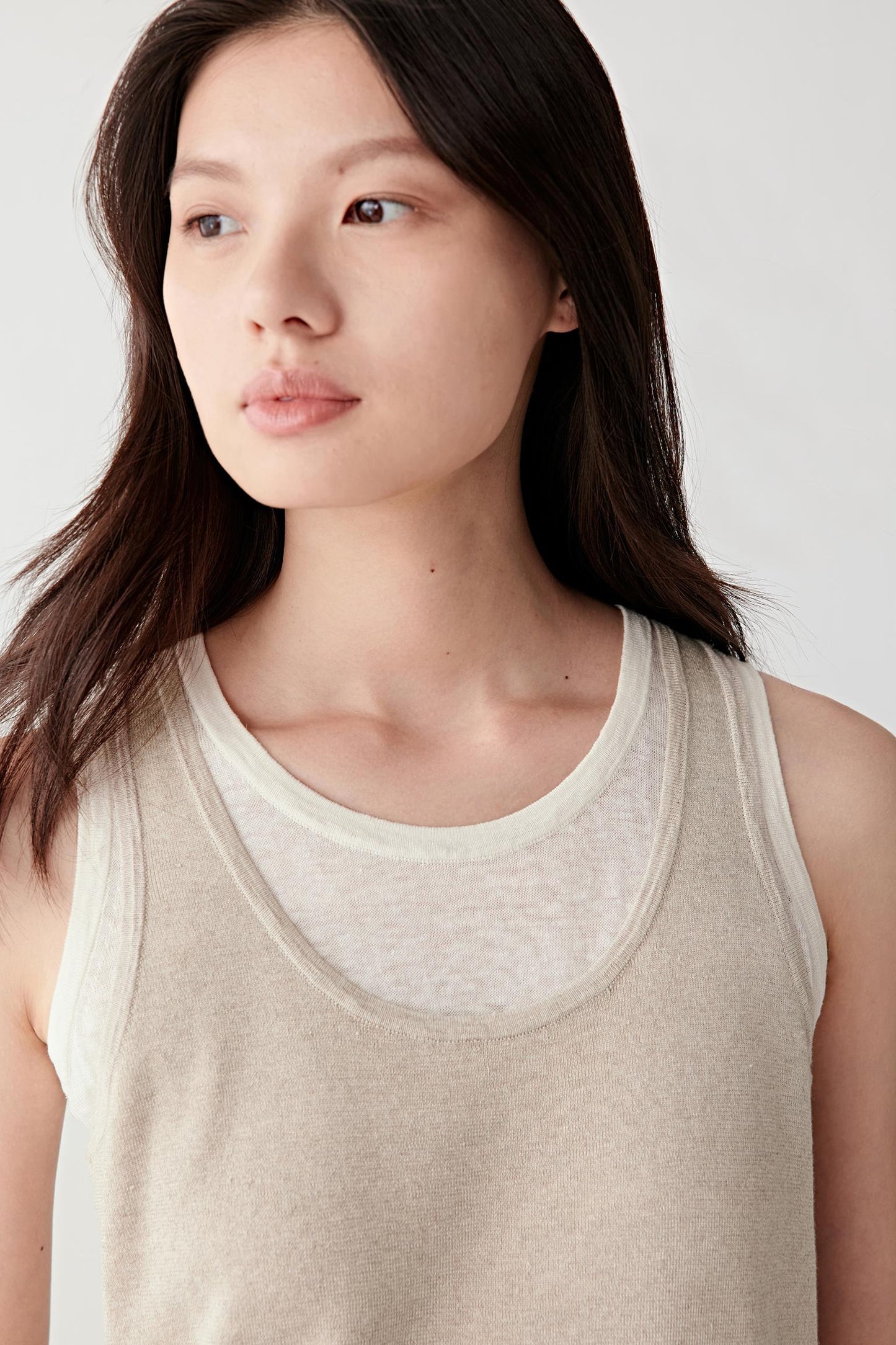 Close-up portrait focusing on the layered neckline and upper knit construction, detailing the subtly sheer texture and natural irregularities of the yarn surface