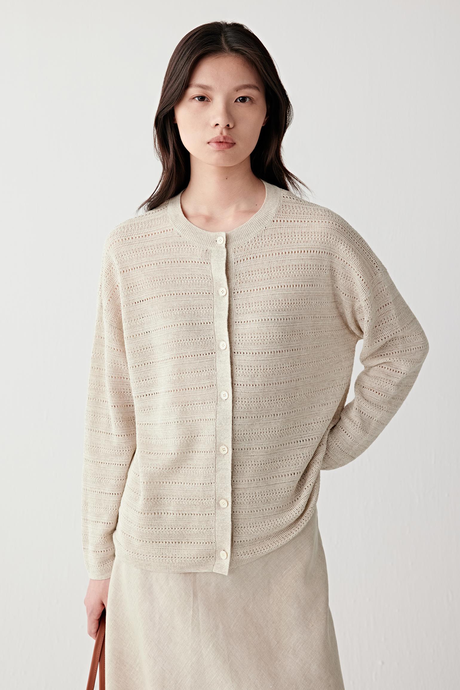 Front view of a woman wearing a beige melange linen and silk cardigan with a lightweight openwork knit construction, highlighting the relaxed silhouette, soft drape and textured knitted surface