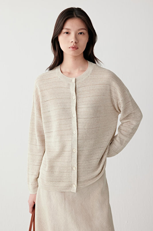 Front view of a woman wearing a beige melange linen and silk cardigan with a lightweight openwork knit construction, highlighting the relaxed silhouette, soft drape and textured knitted surface