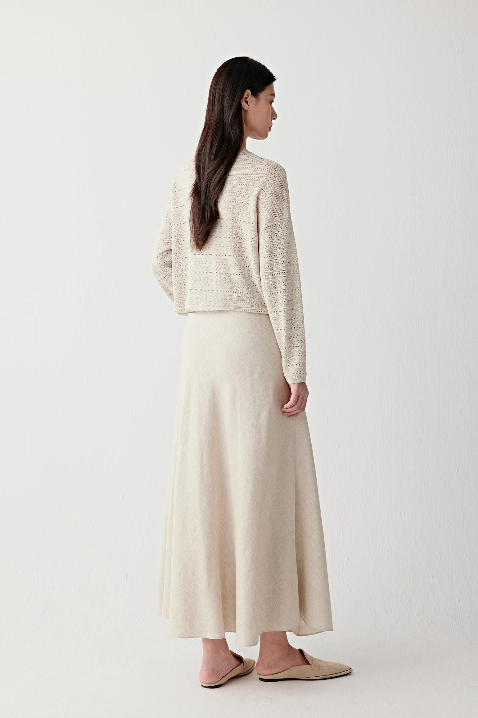 Full-length side or three-quarter view highlighting the elongated silhouette, fluid movement and lightweight drape of the linen and silk knit fabric