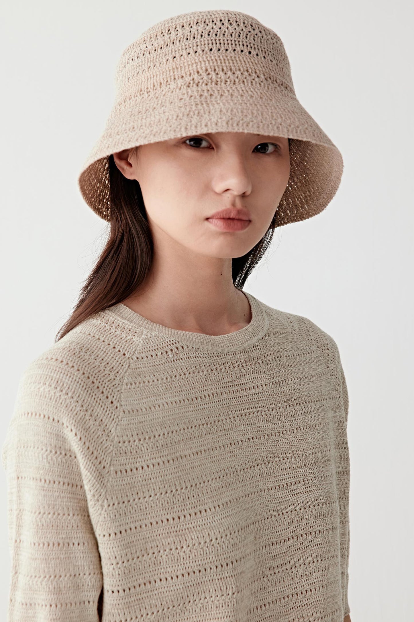 Close-up portrait focusing on the neckline and knit texture, detailing the melange yarn effect and lightly textured surface