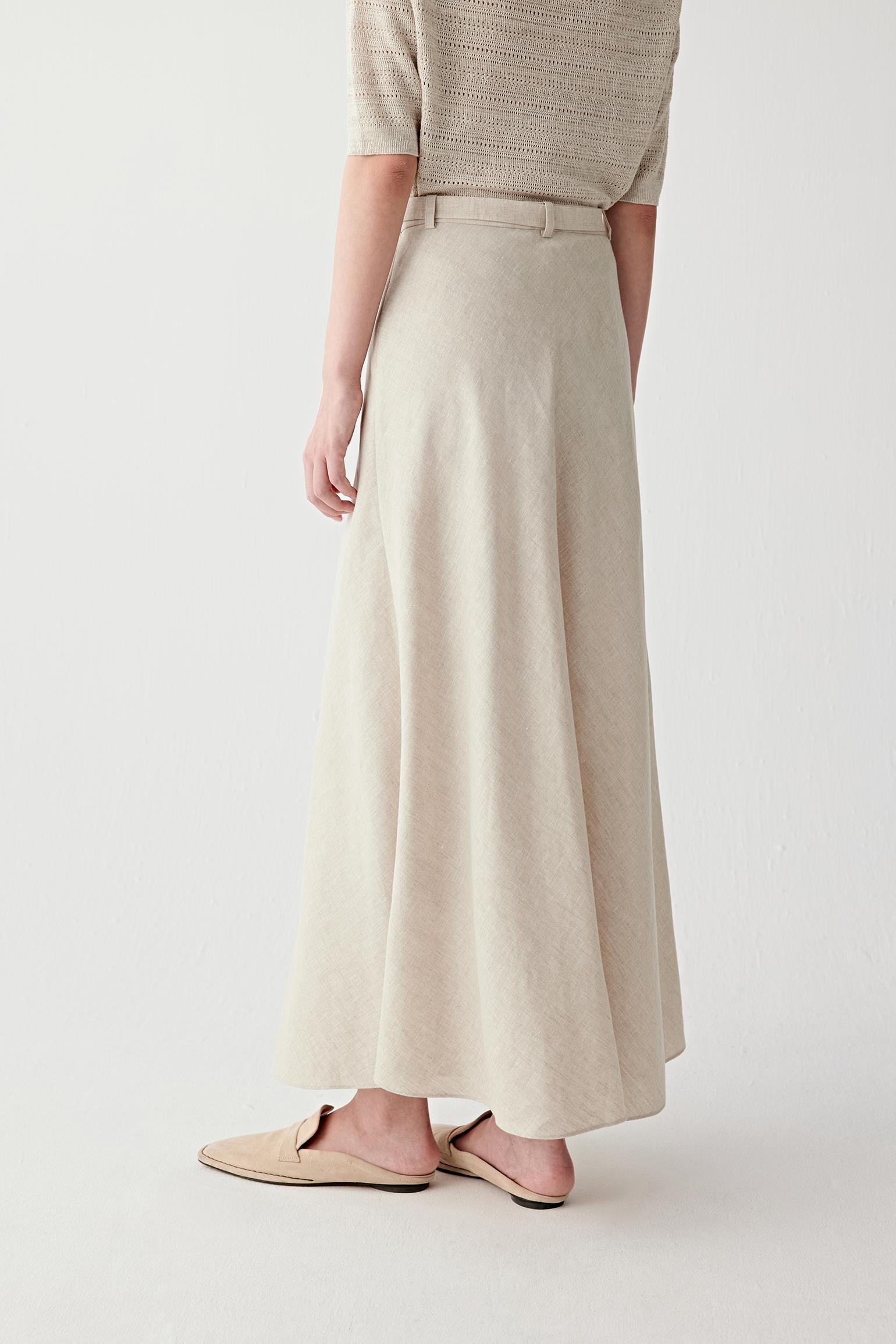 Side or three-quarter rear view showing the elongated silhouette, soft movement and natural texture of the undyed beige linen weave