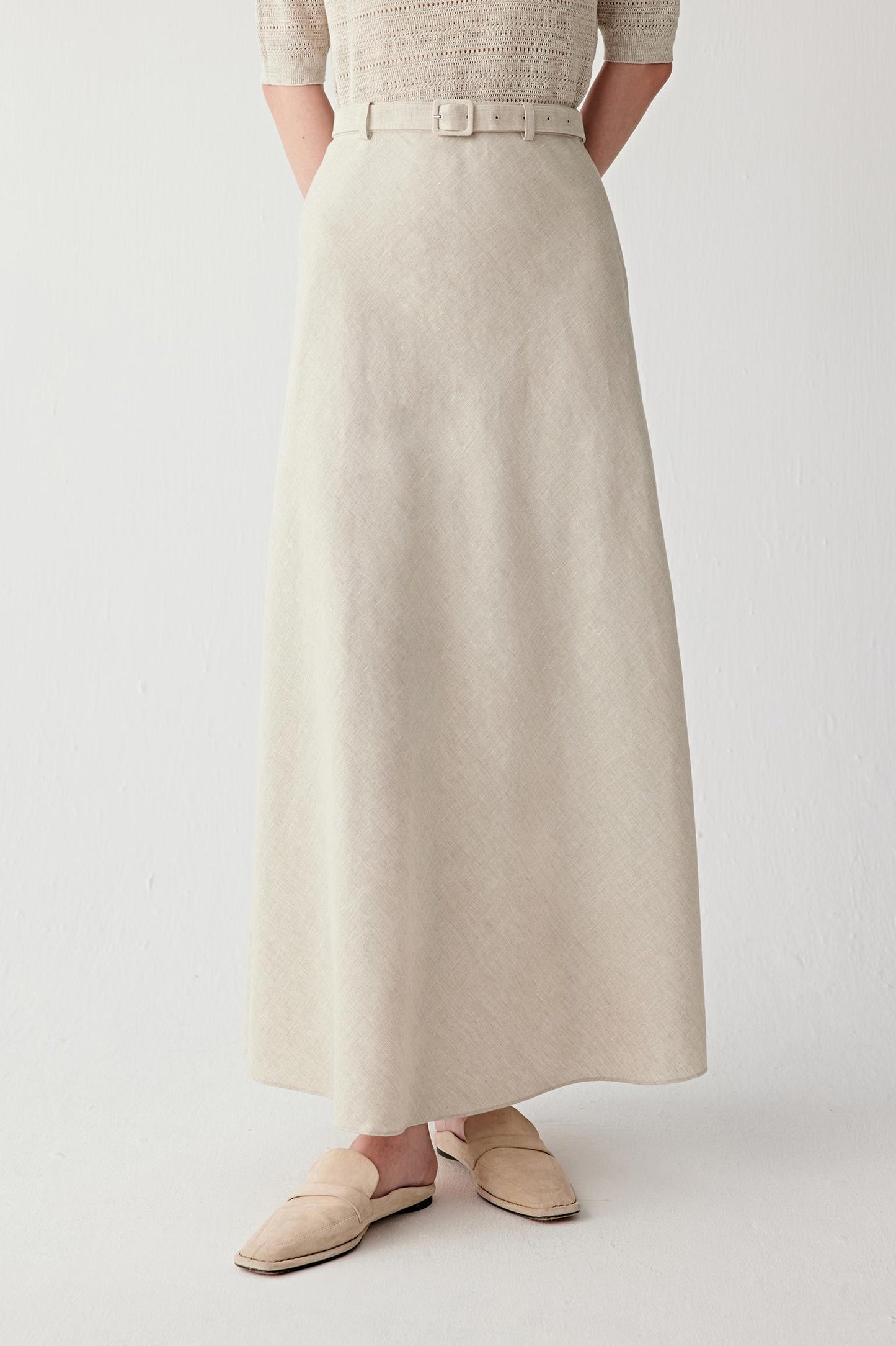Front view focusing on the long flared silhouette and hemline, emphasizing the fluid movement and softly structured drape created by the plain-woven linen fabric