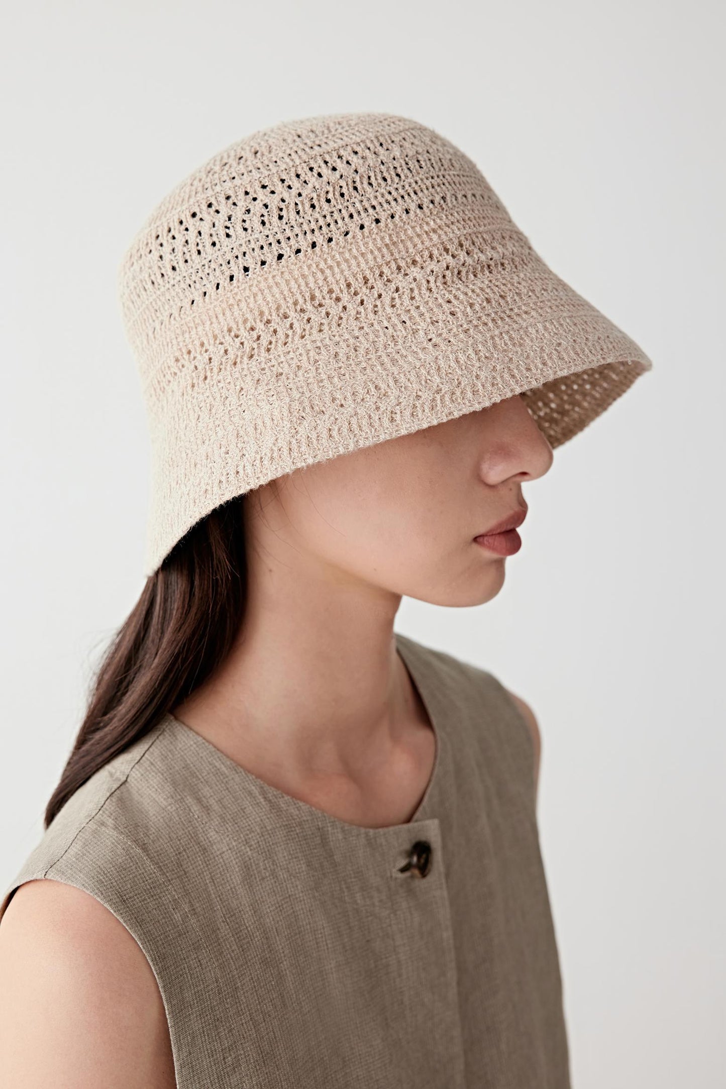 Side profile view highlighting the shape of the brim, its soft downward curve and the breathable open-knit structure, allowing light to pass through the fabric