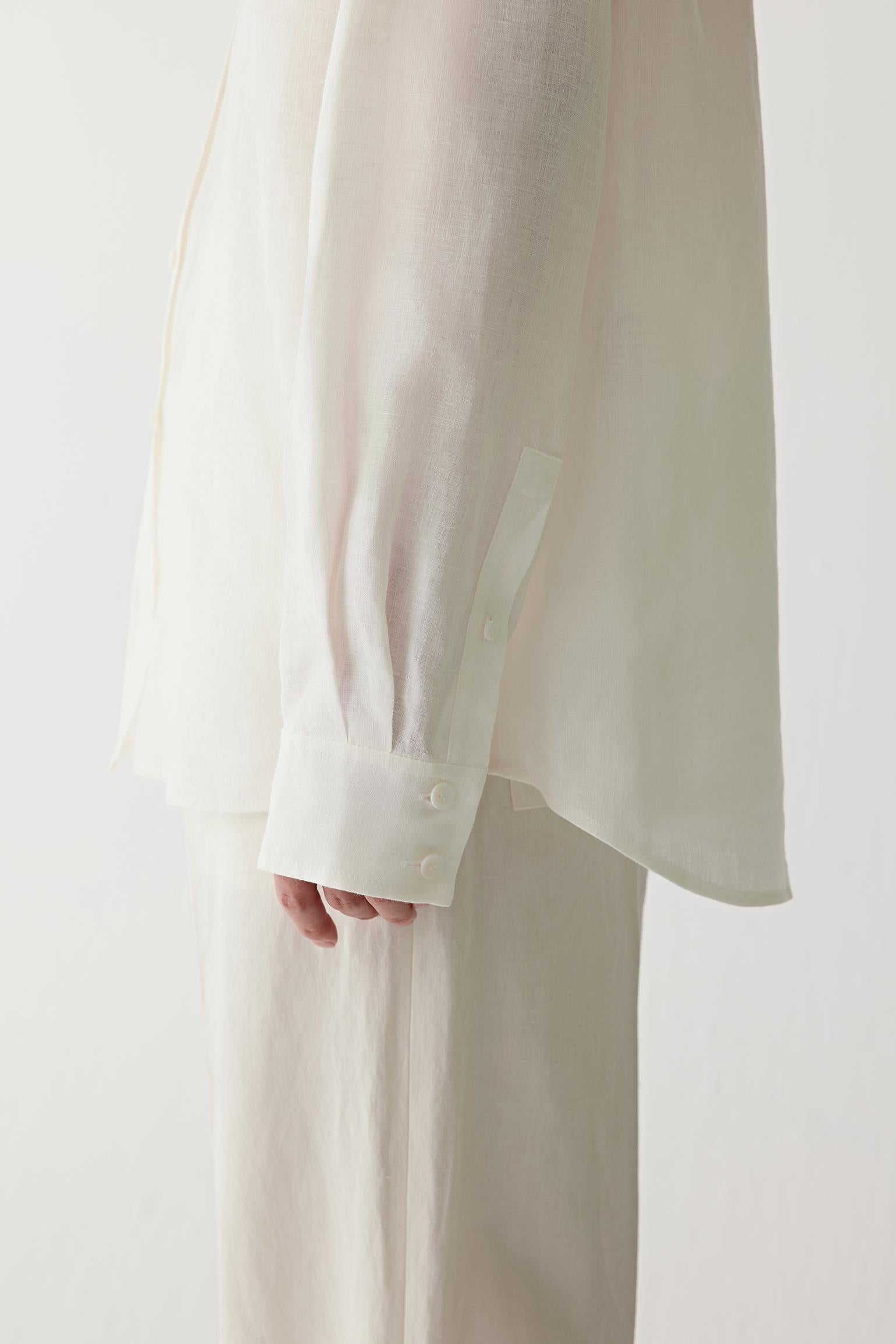 Close-up of cuff and fabric texture showing the buttoned cuff construction, visible stitching and subtle irregularities characteristic of linen weave