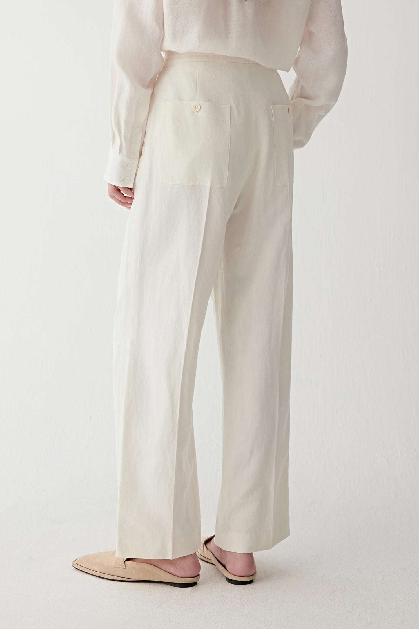 Three-quarter back or side view highlighting the rear construction, clean silhouette and softly flowing drape, with the fabric revealing subtle tonal variation and natural texture