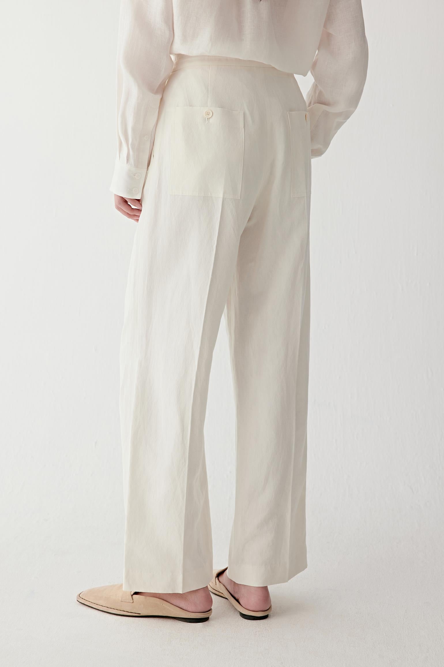 Three-quarter back or side view highlighting the rear construction, clean silhouette and softly flowing drape, with the fabric revealing subtle tonal variation and natural texture