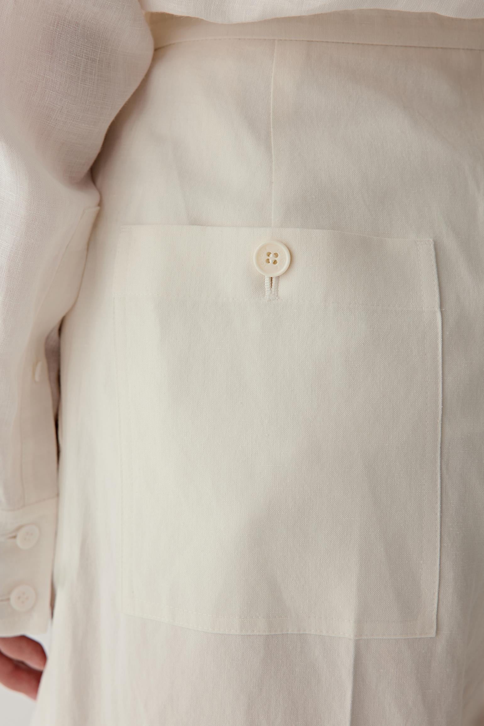 Close-up of back pocket and side seam showing the buttoned patch pocket, clean finishing and lightly textured silk and linen weave