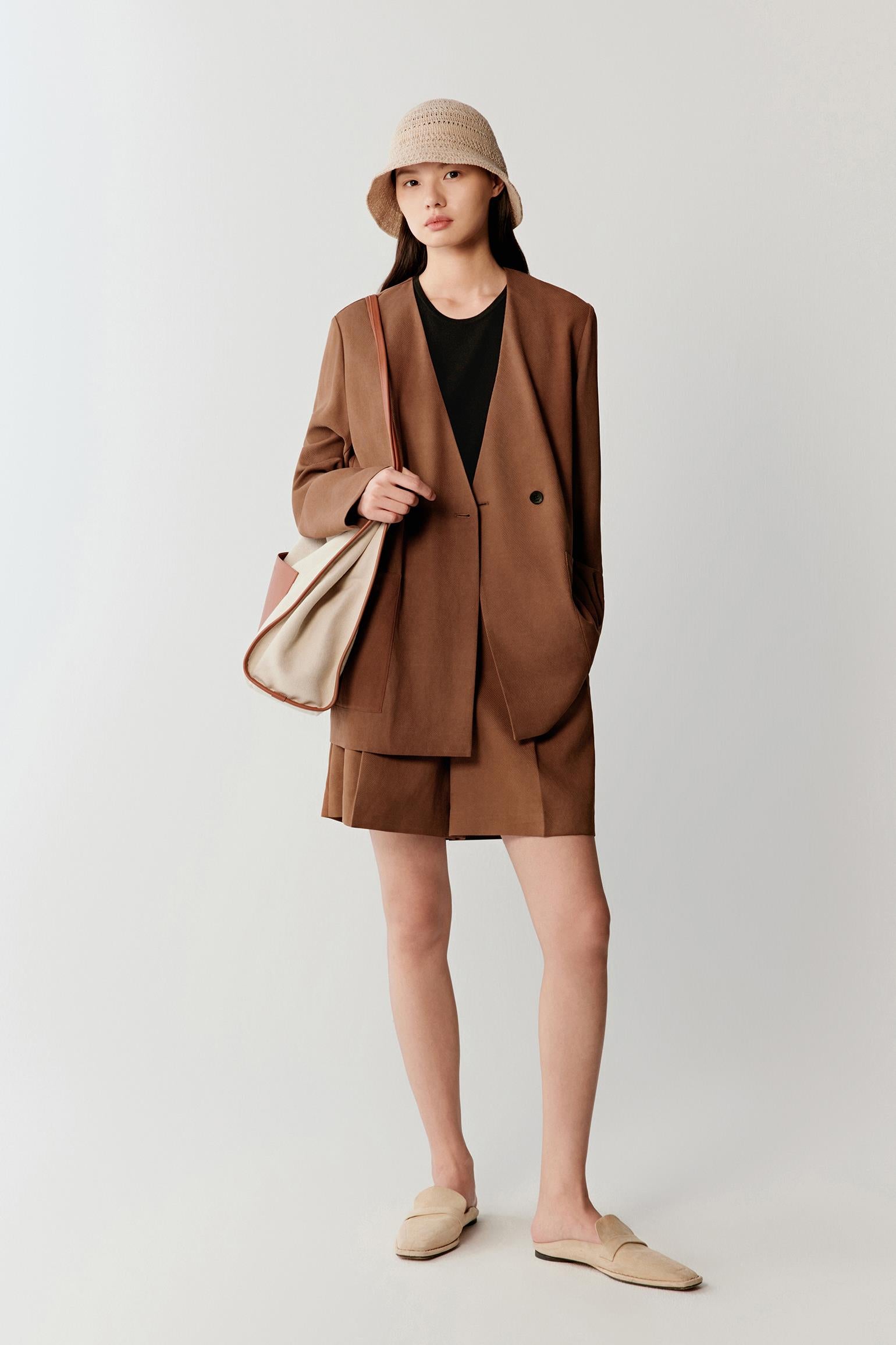 Full-length front view showing the oversized proportions, double-breasted construction and patch pockets, emphasizing the lightweight drape and tonal depth developed through the Gambiered Canton Gauze dyeing process