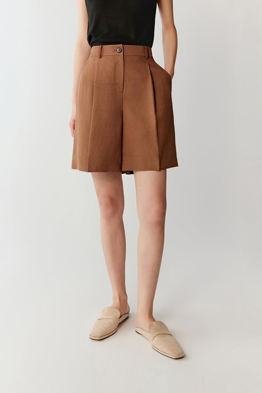 Front view focusing on the leg shape and length of the shorts, emphasizing the high waist, front pleats and softly structured drape of the fabric
