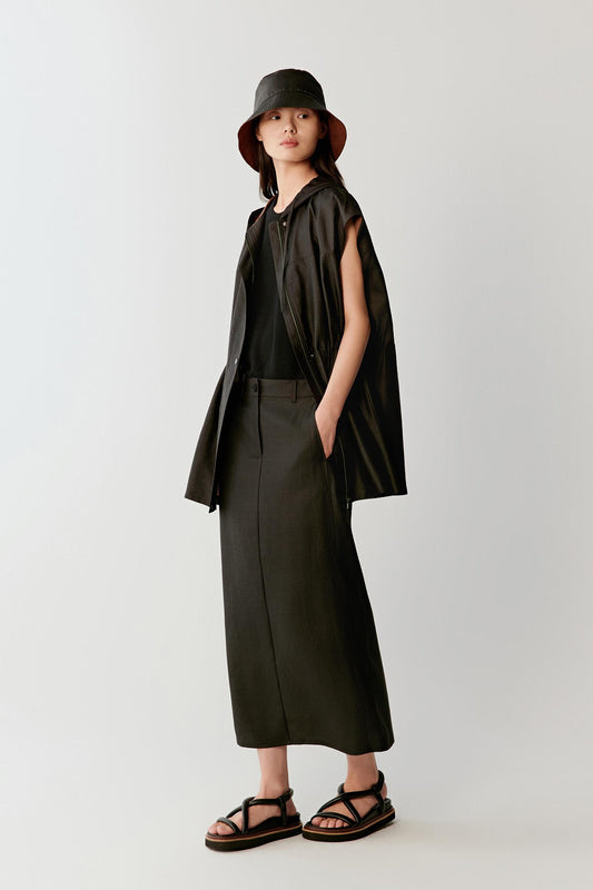 Full-length front view of a woman wearing a deep black skirt in Gambiered Canton Gauze, highlighting the fluid drape, compact woven structure and subtle tonal depth developed through the traditional mud-dyeing and sun-drying process