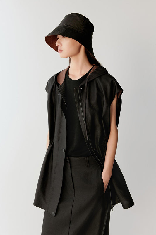 Three-quarter front view showing the sleeveless jacket layered over a matching dress, emphasizing the fluid movement, concealed fastening and drawstring waist that shapes the silhouette